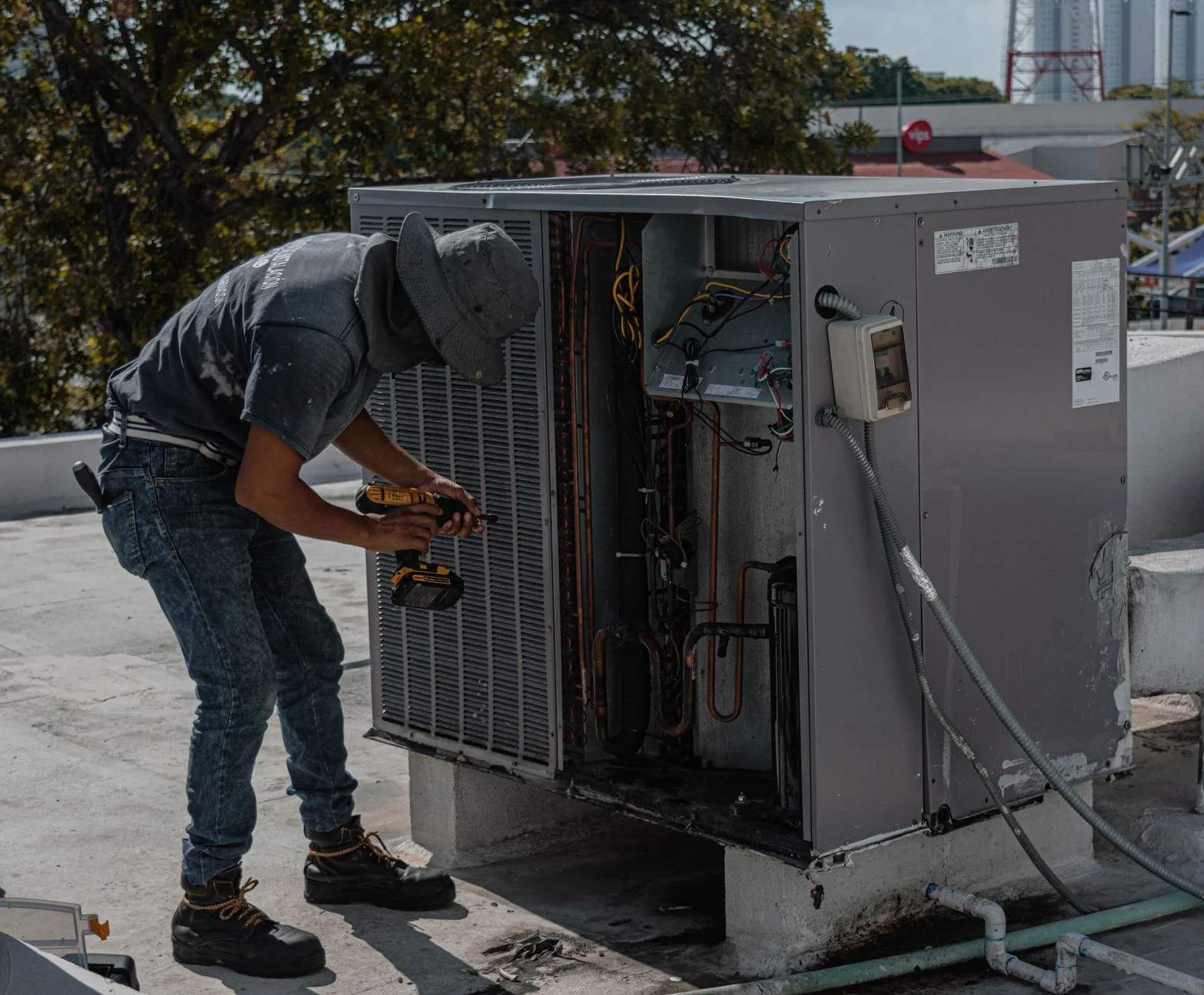 Technician inspecting an outdoor AC condenser coil coated in dust